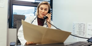 physician-on-phone-examining-medical-reports_soc